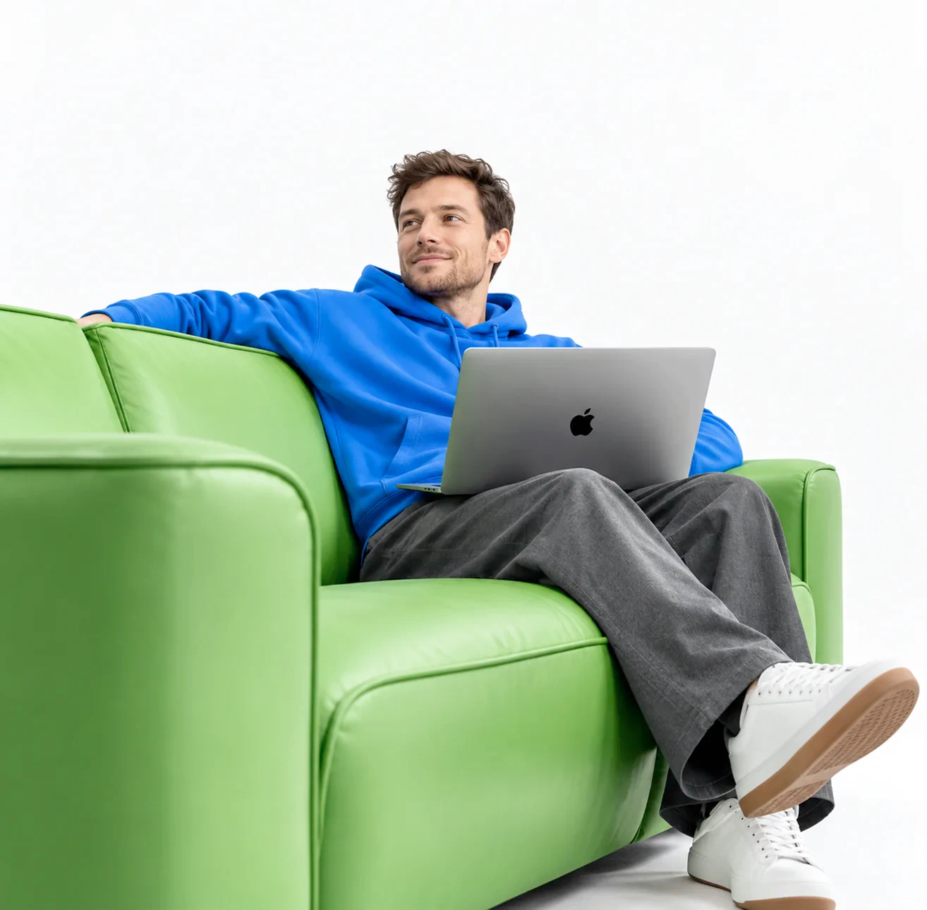 A seller on a green sofa researching Amazon products on a laptop
